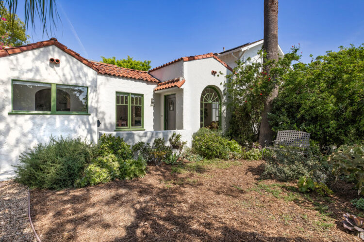 exterior of a spanish style home painted white with saltillo tile roof and sage trim windows