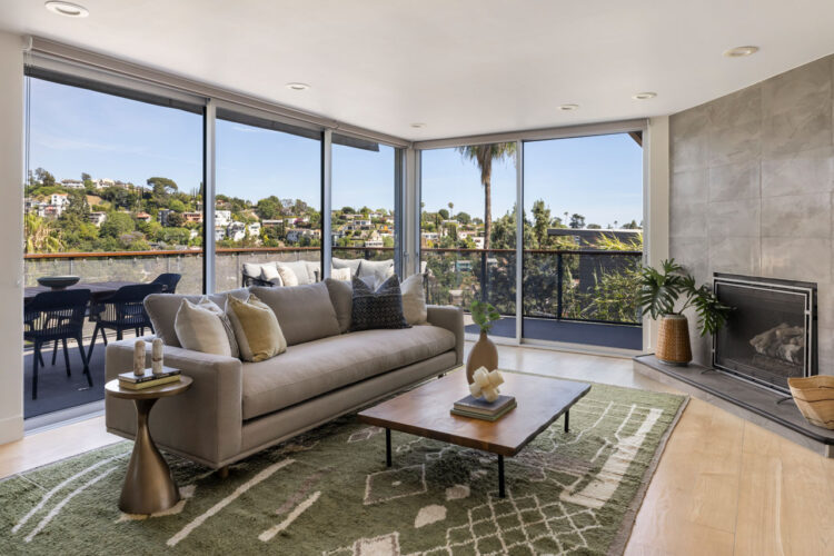 living room with grey couch, fireplace, and view of dtla from a house balcony