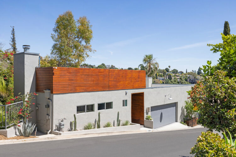 exterior of a contemporary hillside home painted grey surrounded by trees
