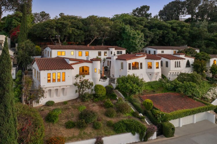 twilight drone image of a majestic spanish style duplex with white stucco and saltillo tile roof