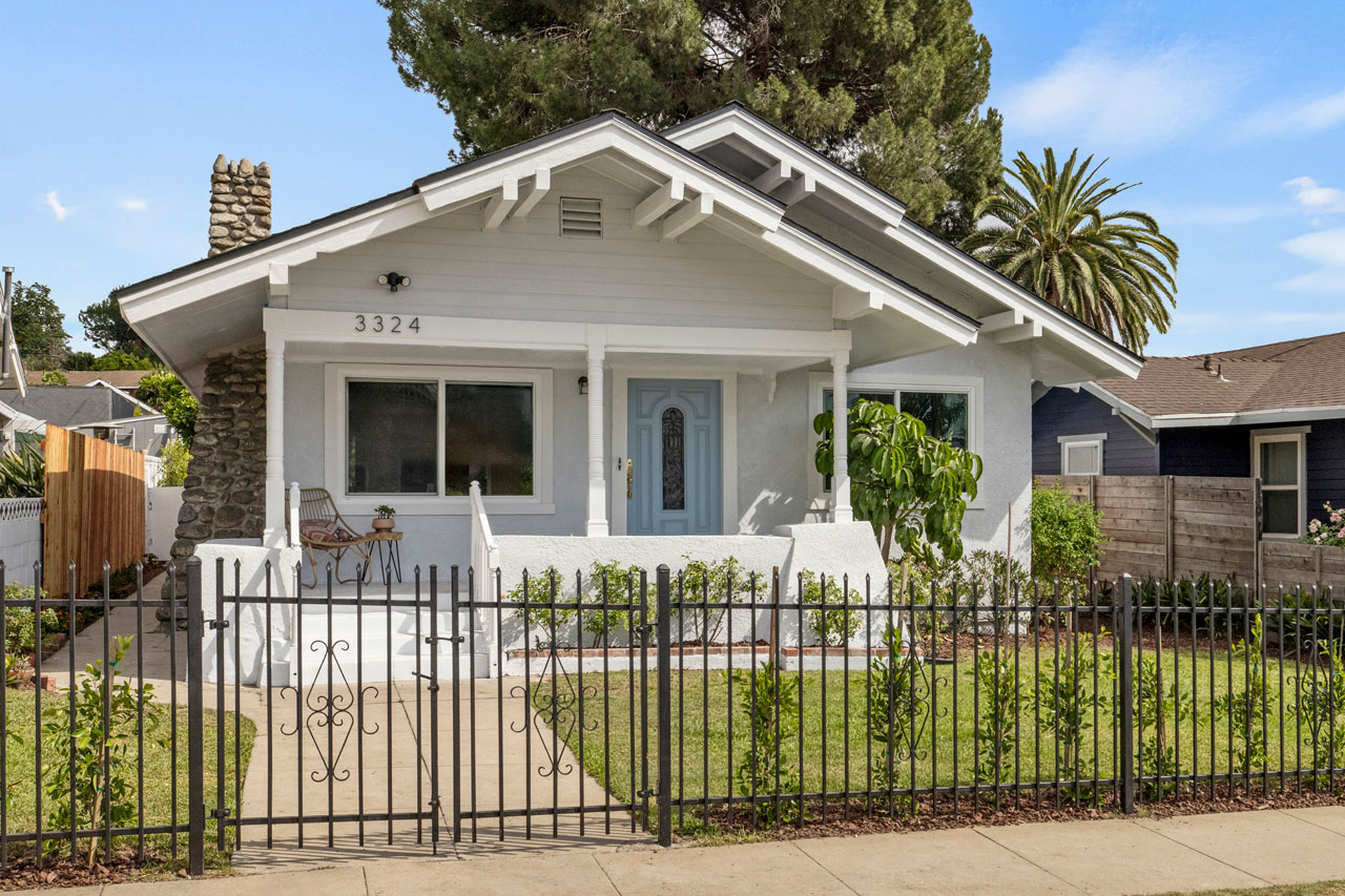 exterior of a california bungalow painted grey with white trim and blue door