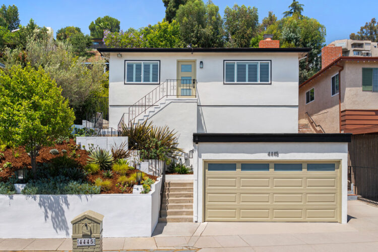 exterior of a traditional hillside home with a garage and white home up a flight of stairs