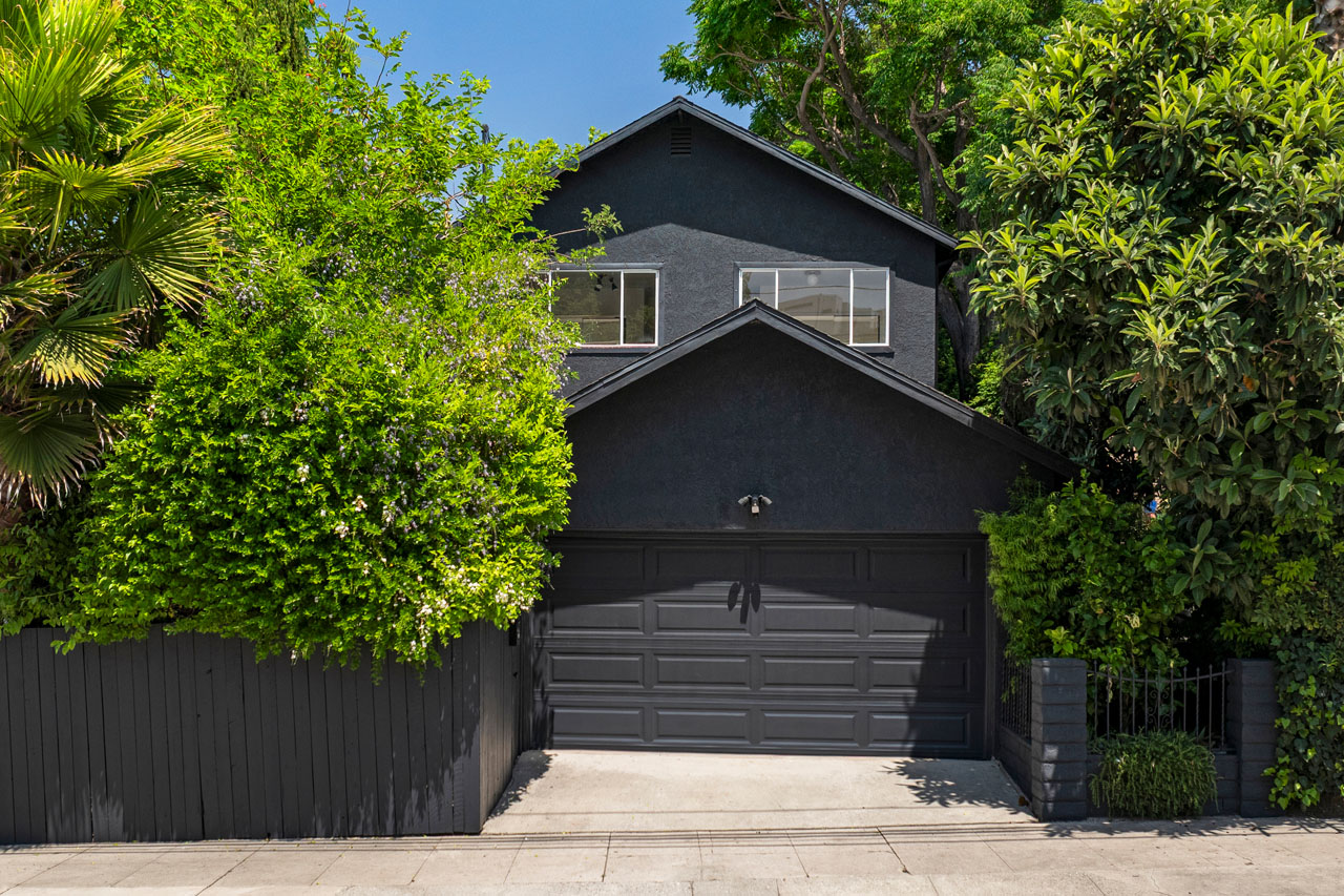 exterior of a two story home painted black with white trim and green surrounding trees