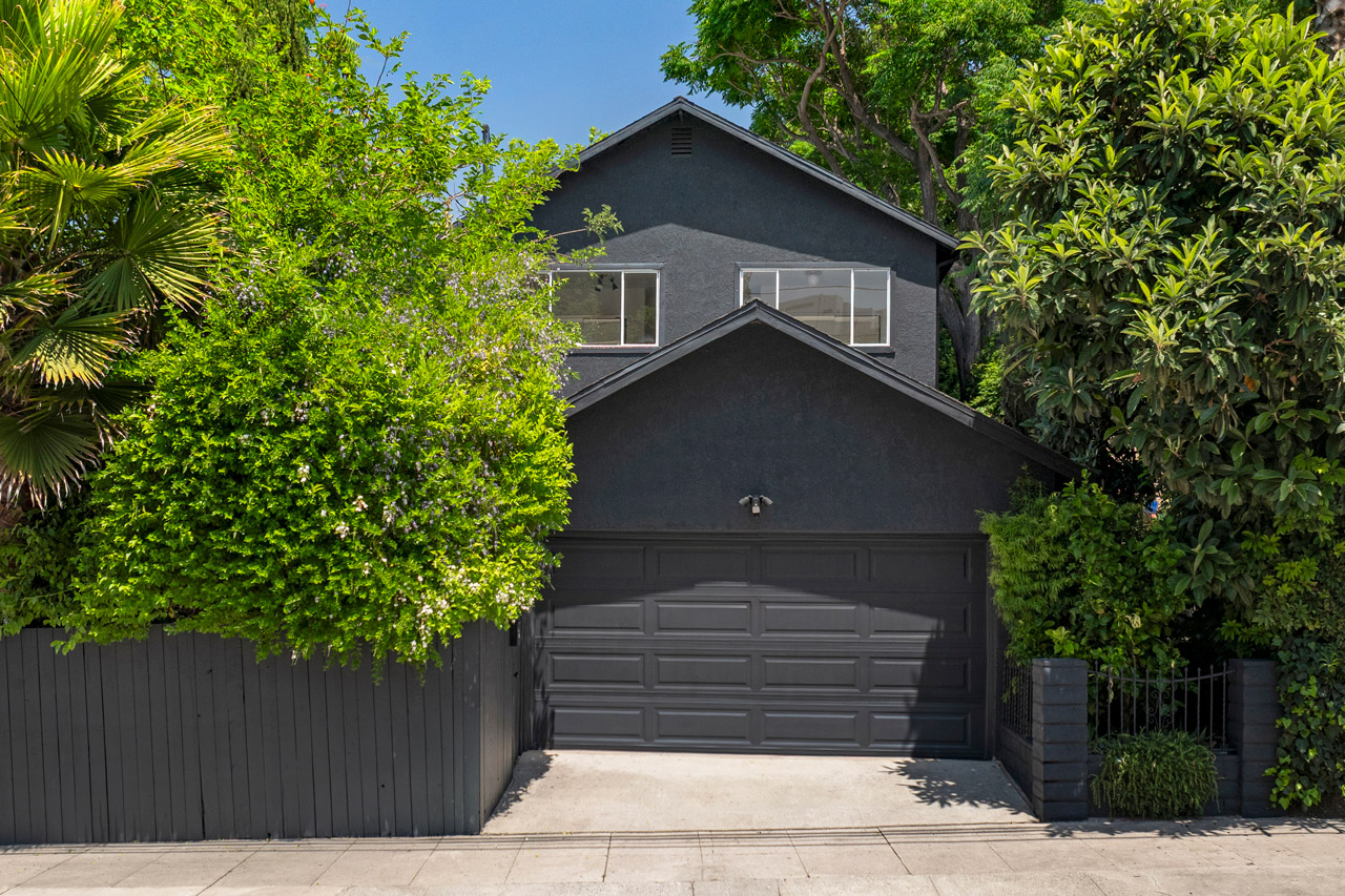 exterior of a two story home painted black with white trim and green surrounding trees