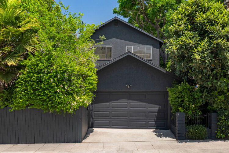exterior of a two story home painted black with white trim and green surrounding trees