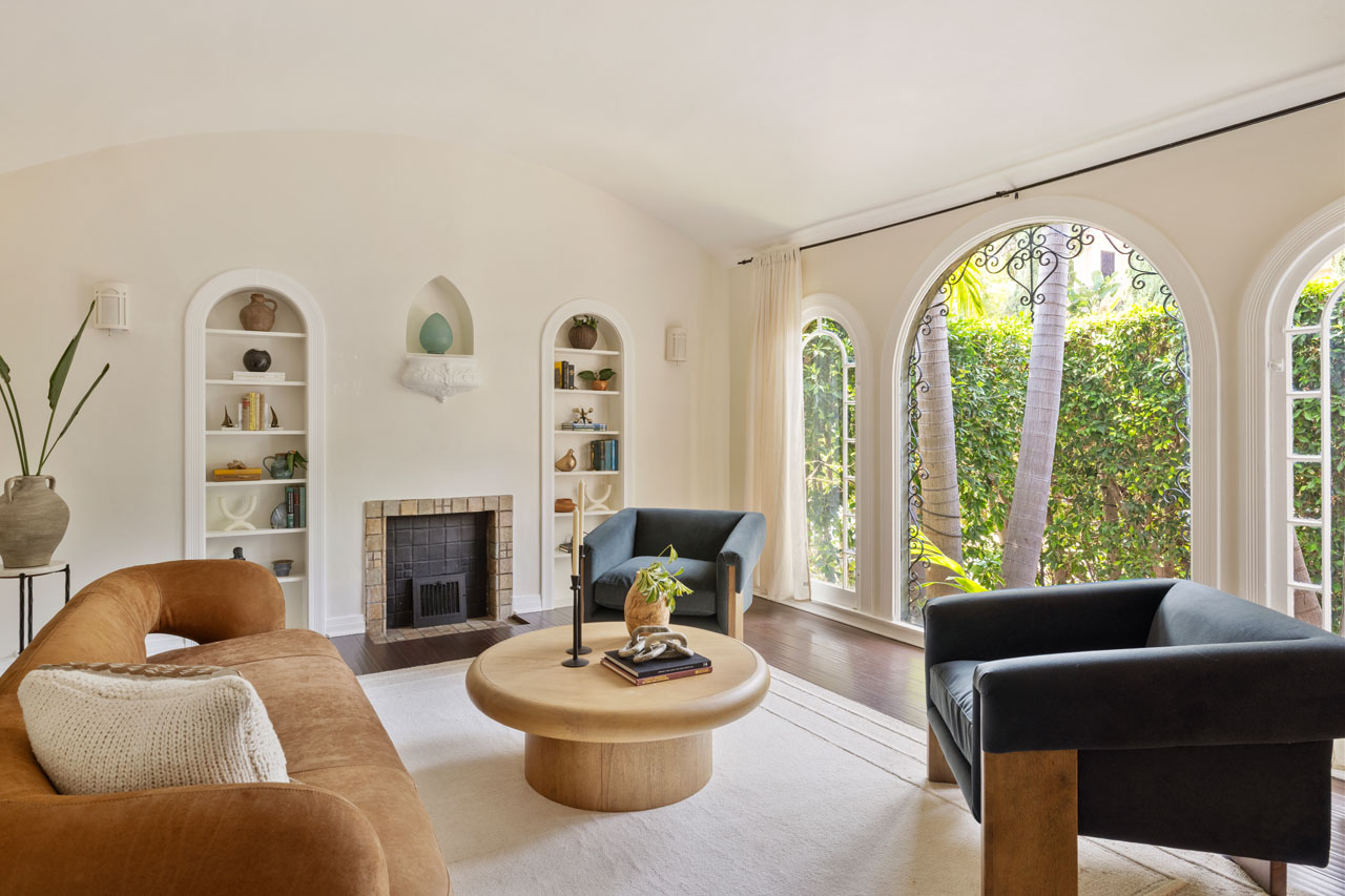 interior of a spanish style living room painted white with batchelder fireplace and arched windows