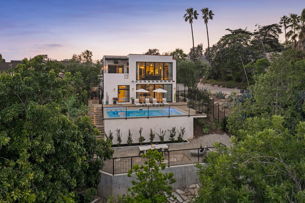twilight exterior of a spanish style home two story contemporary with a pool and palm trees in distance