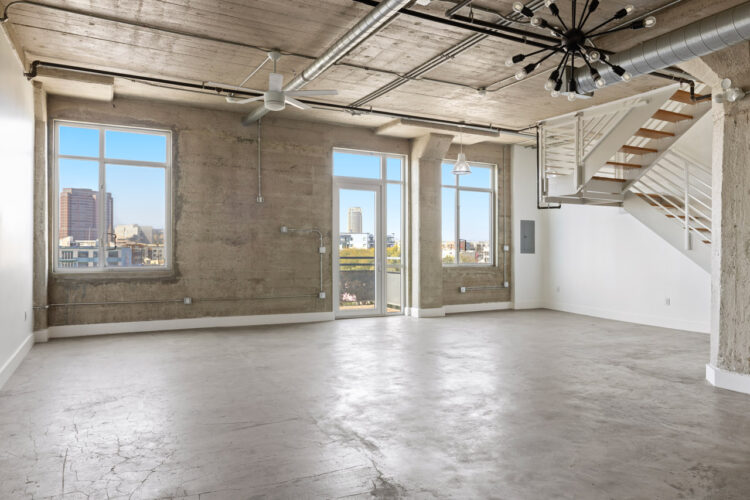 image of a loft with concrete floors, white walls and windows with a city view