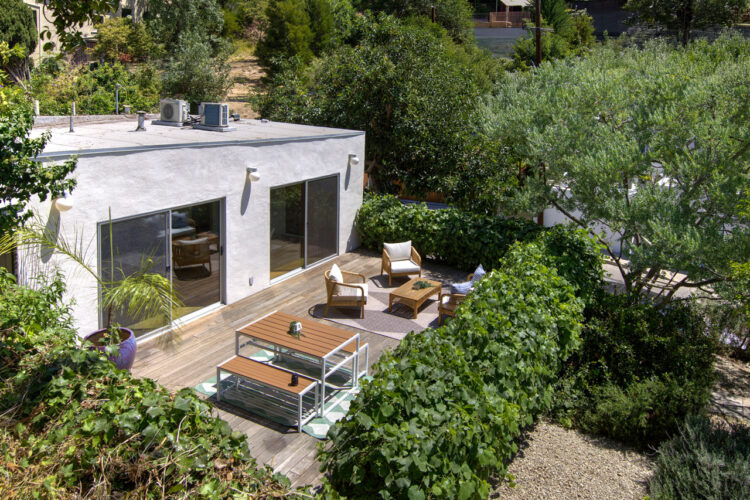 drone image of a traditional home painted light grey with a wooden patio