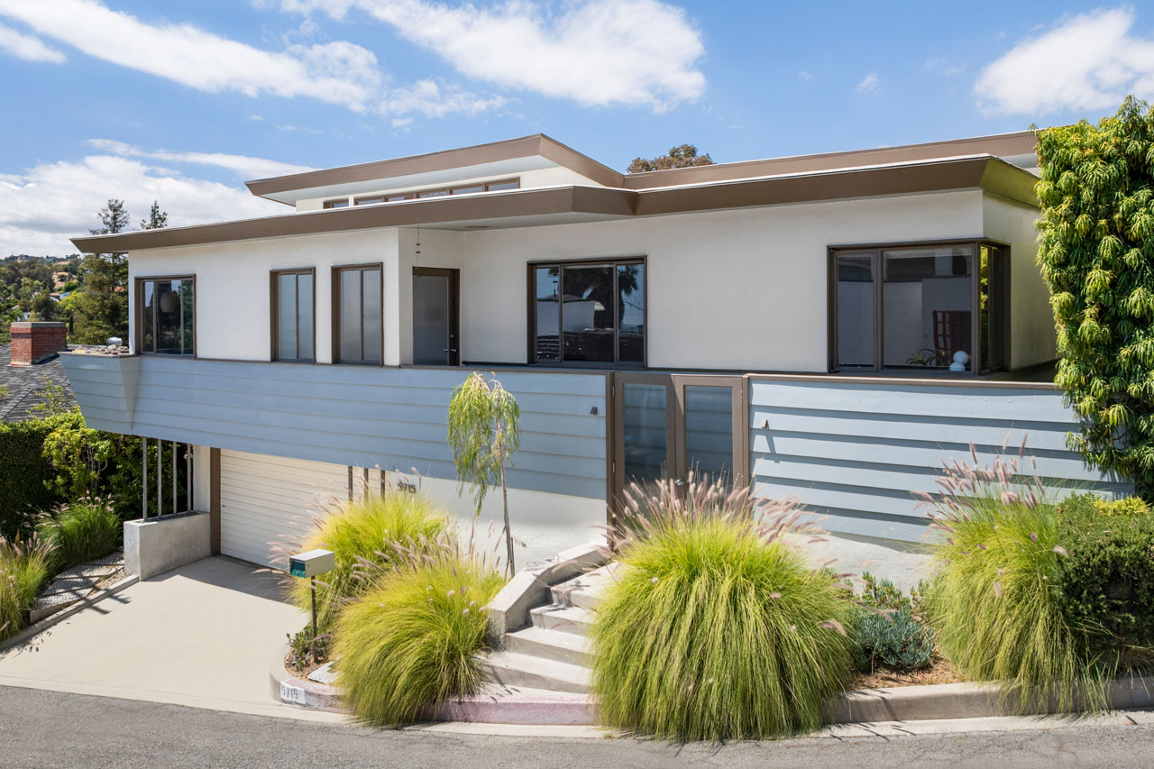 exterior of a midcentury modern home painted white with brown tree