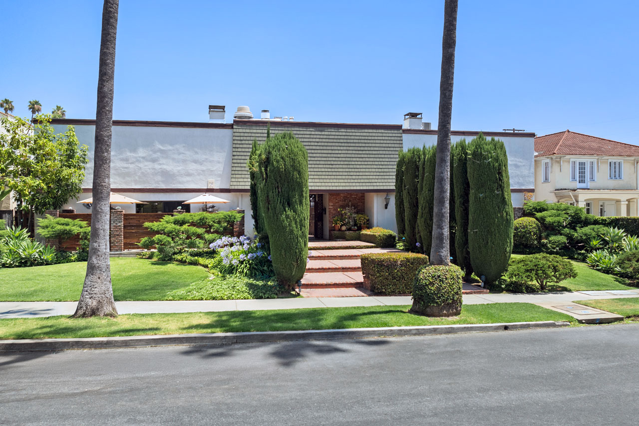 exterior of a two story condo building with green grass and cypress bushes