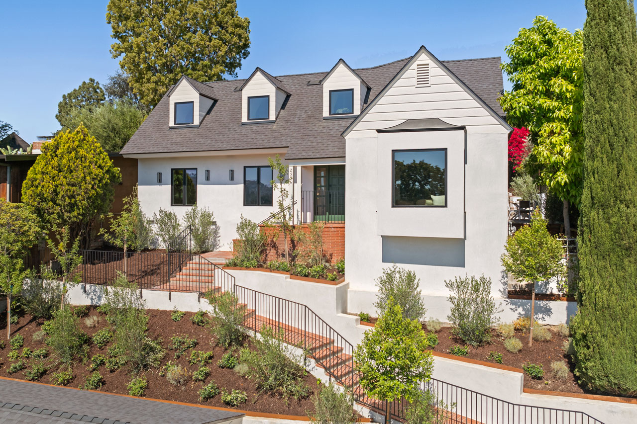 A traditional Silver Lake home in the Moreno Highlands from Tracy Do Real Estate. exterior of a traditional two story home with garage, painted white with black roof cypress tree and brick details