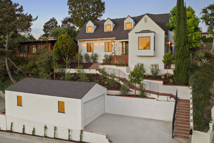 exterior of a traditional two story home with garage, painted white with black roof cypress tree and brick details