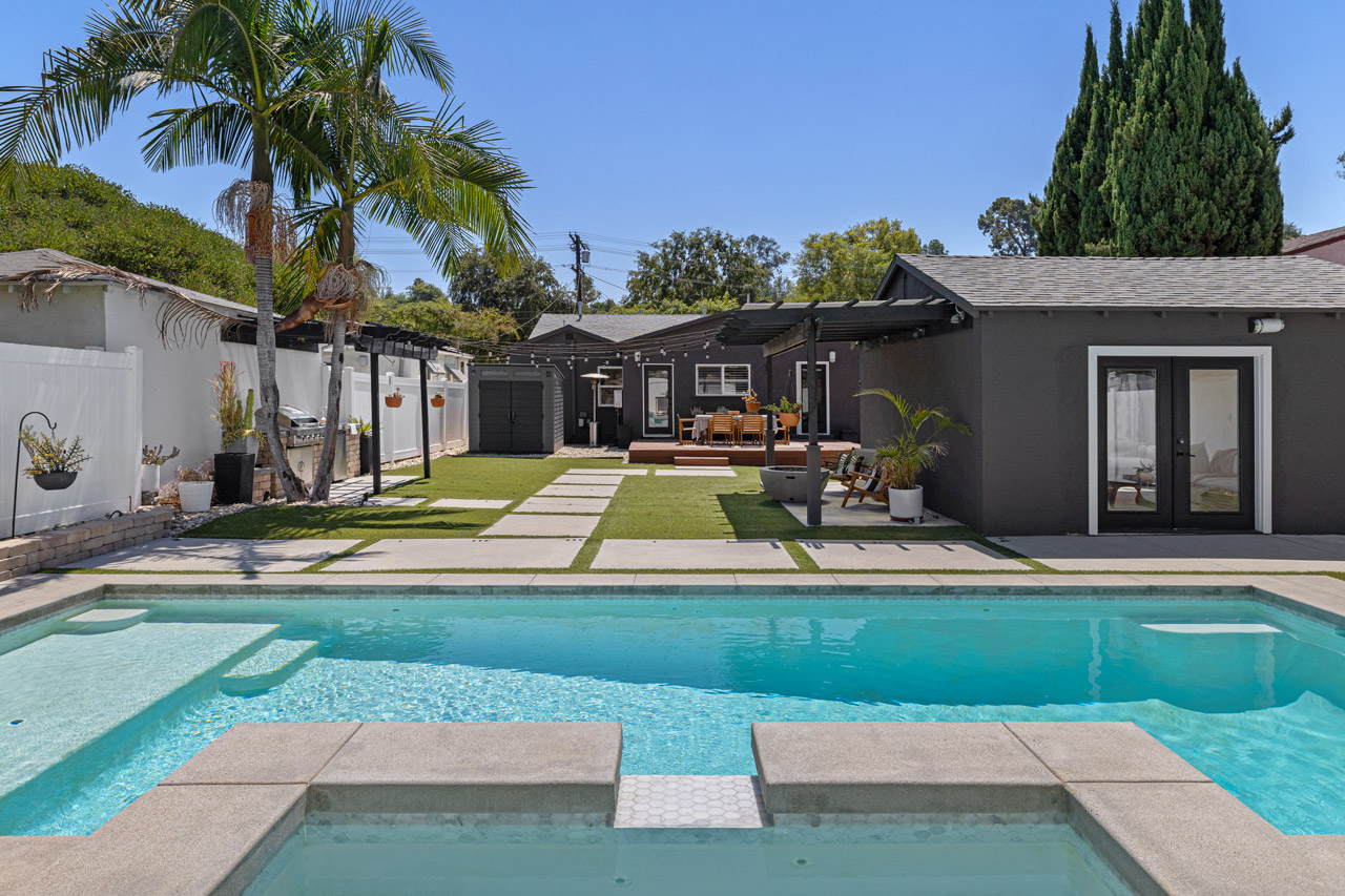 backyard with a pool and grey traditional home with green yard
