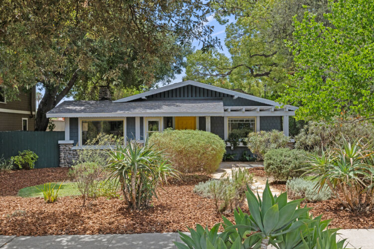 exterior of a craftsman bungalow home painted blue with white trim and a yellow door