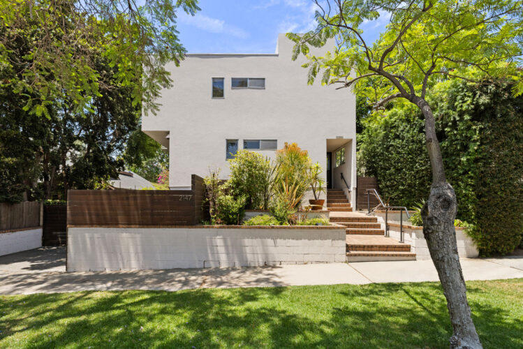 exterior of a two story condo building painted white with green trees and grass