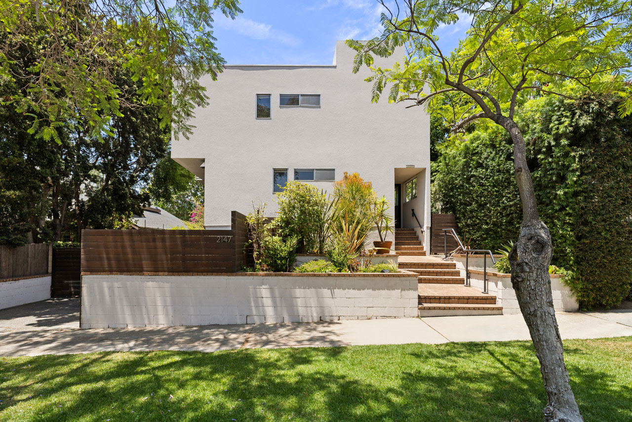 exterior of a two story condo building painted white with green trees and grass