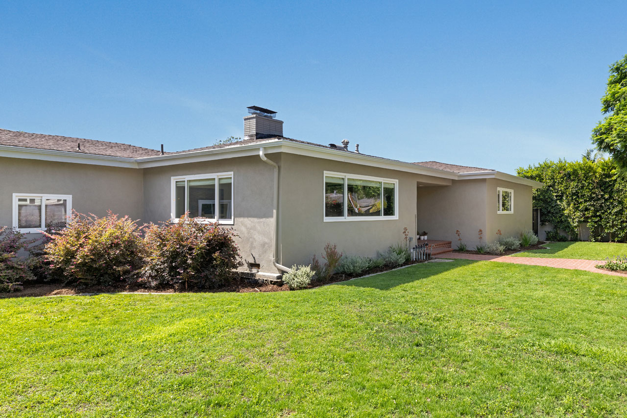 exterior of a ranch style home painted grey with green yard and blue sky
