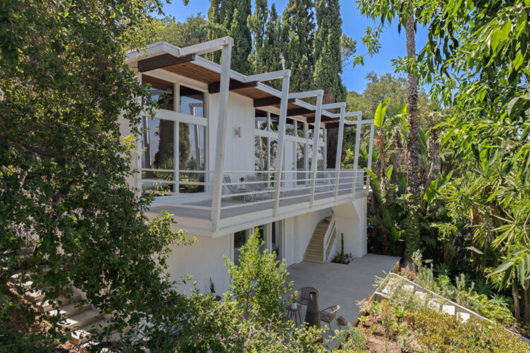 exterior of a mid century style home painted grey with white trim and eaves
