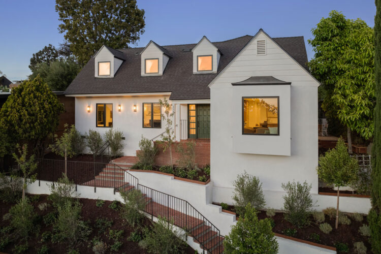 exterior of a traditional two story home with garage, painted white with black roof cypress tree and brick details