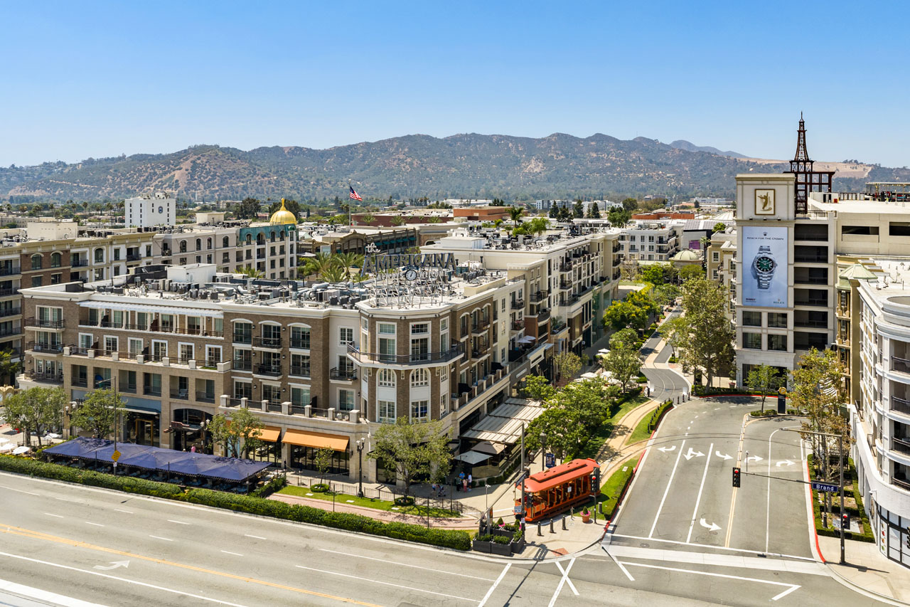 drone image of the americana in glendale california, showing a mall, tower, road, and hills in the background