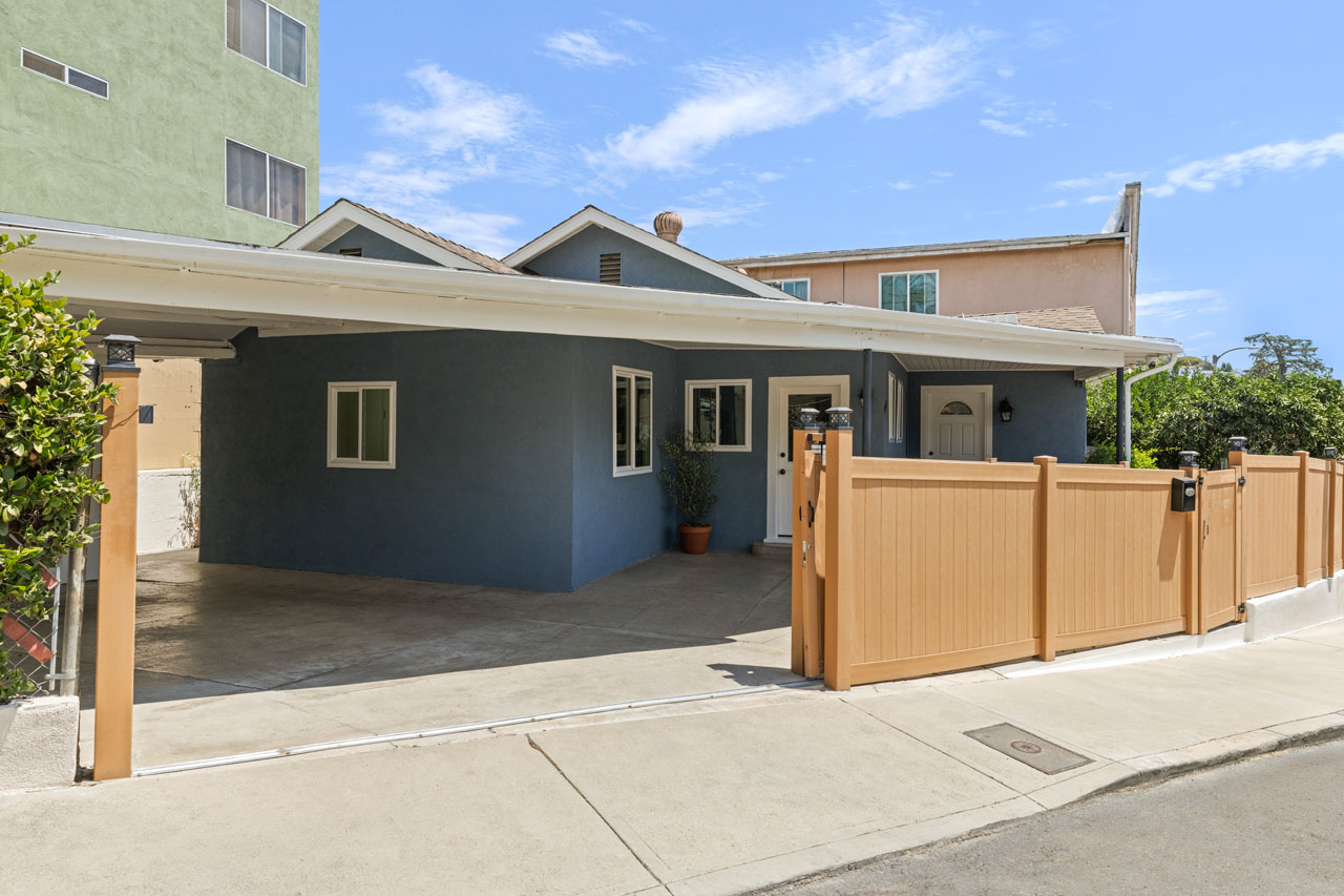 exterior of a traditional style home painted blue with white trim and a wood driveway gate