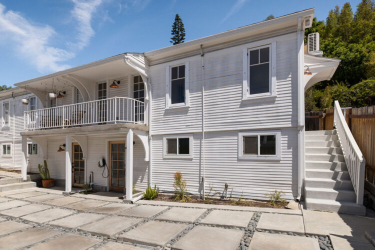 1310 1/2 Lucile Ave Silver Lake Apartment with Flex Space for Rent Tracy Do Real Estate. Image of a two story apartment building painted white with large concrete pavers and a blue sky