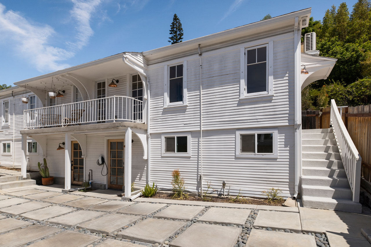 1310 1/2 Lucile Ave Silver Lake Apartment with Flex Space for Rent Tracy Do Real Estate. Image of a two story apartment building painted white with large concrete pavers and a blue sky